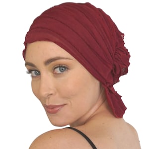 May include: A burgundy, crinkled fabric head covering with a loose, flowing style. The fabric is gathered at the back of the head, creating a soft, voluminous look.