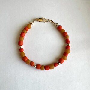 May include: A bracelet made with orange and brown beads and silver accents.