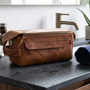 Executive leather dopp kit sitting near a sink, showing its water-resistant finish in a bathroom setting.