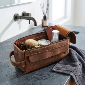 Professional leather wash bag for men placed on a high-end dark marble bathroom vanity.
