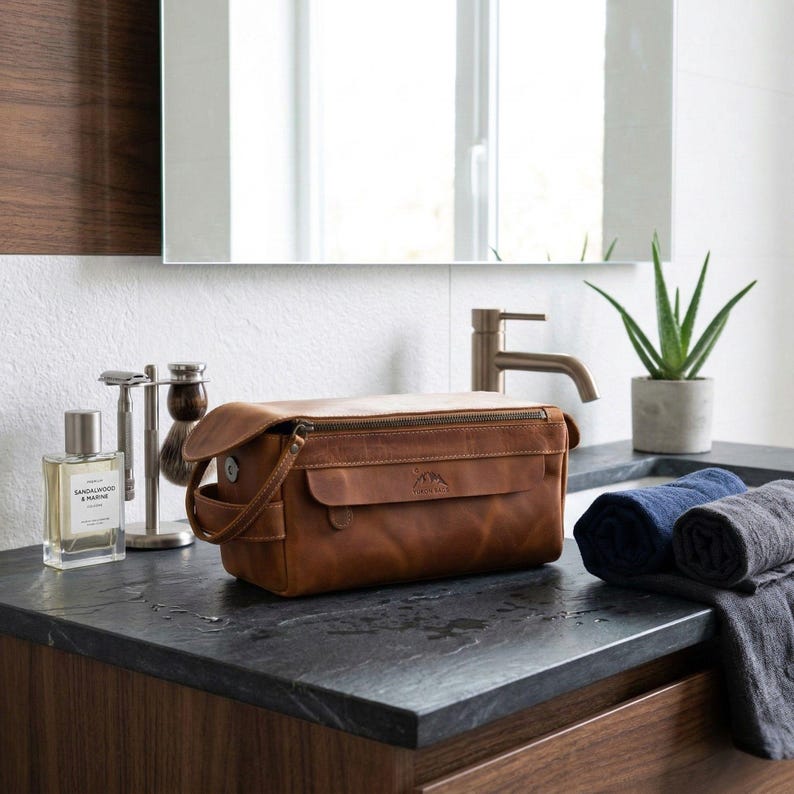 Executive leather dopp kit sitting near a sink, showing its water-resistant finish in a bathroom setting.