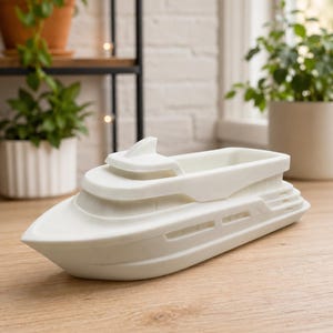 May include: A white, matte-finished yacht-shaped container with a hollow interior. The vessel features a pointed bow, a tiered cabin structure, and horizontal window cutouts along the hull, presented as a singular decorative object.