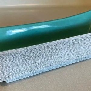 May include: A teal glazed ceramic planter with a white textured exterior. The planter is rectangular with rounded edges and a slightly curved top.