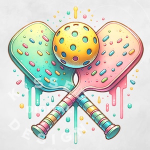 May include: Two colorful pickleball paddles with a yellow pickleball in the center. The paddles are decorated with sprinkles and have dripping icing. The background is white with colorful dots.