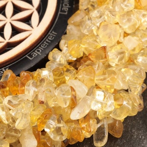 Peut inclure: Gros plan sur un brin de pépites de citrine jaune. Les pépites sont de forme irrégulière et ont une apparence translucide. Les pépites de citrine sont disposées en un motif lâche et fluide.