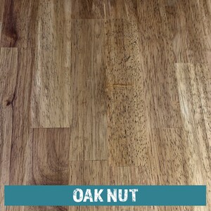 May include: Close-up of a wood grain surface with a light brown color. The wood has a natural, knotty texture. The text "OAK NUT" is printed in white on a teal blue background at the bottom of the image.