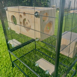 May include: A black metal cage with wooden platforms and a wooden playhouse. The cage has a wire mesh design and is on wheels.