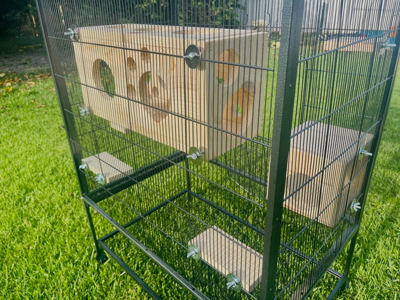 May include: A black metal cage with wooden platforms and a wooden playhouse. The cage has a wire mesh design and is on wheels.