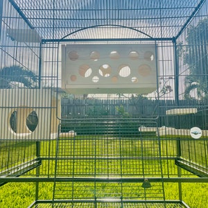 May include: A large black metal cage with multiple wooden platforms and a white wooden perch. The cage is designed for small animals like birds or rodents.