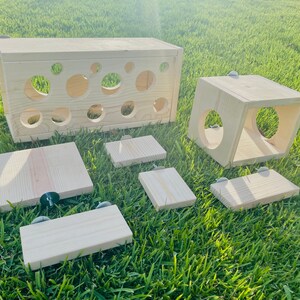 May include: A set of wooden enrichment toys for small animals, including a tunnel, a cube, and several platforms. The toys are made of natural wood and have a light brown color.