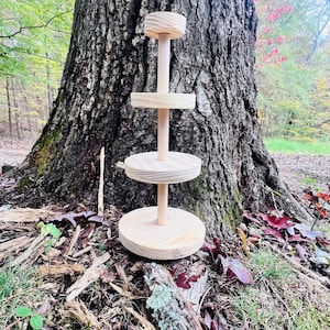 May include: A three-tier wooden stand with a natural finish. The stand is made of unfinished pine wood and has a rustic look. It is perfect for displaying small items, such as jewelry, candles, or plants.