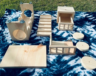 May include: A set of wooden hamster play structures, including a platform, a ramp, a house, and a tunnel. The structures are made of natural wood and are designed to provide enrichment for small pets.