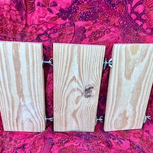 May include: Three wooden boards with metal brackets and screws. The boards are light brown and have a natural wood grain. The boards are arranged horizontally and are attached to each other with the brackets and screws.