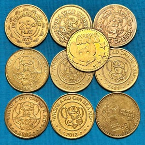May include: Ten gold-colored Chuck E. Cheese's tokens with various designs and dates ranging from 1979 to 2014. The tokens feature the Chuck E. Cheese's mascot, a mouse, and various phrases like "Pizza Time Theatre" and "Where a Kid Can Be a Kid".