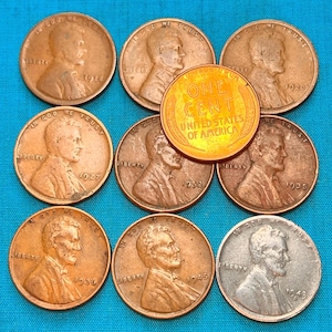 May include: A collection of copper and silver-colored pennies, some with dates visible, including 1914, 1920, 1927, 1935, 1936, 1945, 1948, and 1952. One gold-colored coin reads "ONE CENT UNITED STATES OF AMERICA".