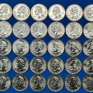 May include: A collection of silver United States quarters arranged in rows and columns on a blue background. Each coin features a profile of George Washington on the obverse. The coins are in good condition.