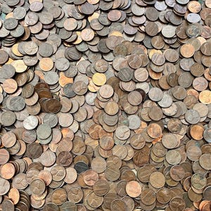 May include: A large pile of copper-colored US pennies. The coins are arranged in a random pattern, creating a textured surface.