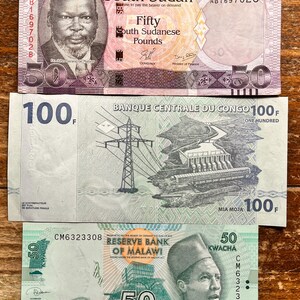 K&ouml;nnte beinhalten: Drei verschiedene Banknoten aus S&uuml;dsudan, Kongo und Malawi. Die s&uuml;dsudanische Banknote ist rosa und lila mit einem Portr&auml;t eines Mannes. Die kongolesische Banknote ist gr&uuml;n und zeigt ein Wasserkraftwerk. Die malawische Banknote ist gr&uuml;n und zeigt ein Portr&auml;t eines Mannes.
