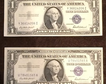 May include: Two vintage US one dollar silver certificates. The top certificate has the serial number Y 36814206 I and the bottom certificate has the serial number U78401565 A. Both certificates feature a portrait of George Washington.