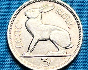 Könnte beinhalten: Eine silberfarbene irische Drei-Pence-Münze mit einem Hasen in der Mitte. Der Text "leat" steht links, "reul" rechts und "3d" ist unten eingeprägt. Die Münze hat einen perlierten Rand und eine metallische Oberfläche.