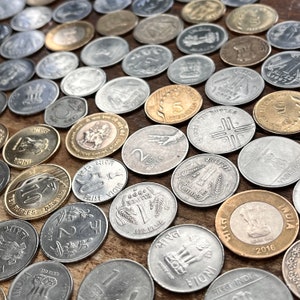 May include: A collection of Indian rupee coins in various denominations, including 1, 2, 5, and 10 rupees. The coins are made of silver, copper, and brass and feature different designs, including the Indian flag, the Ashoka Chakra, and the words "Bharat" and "India".
