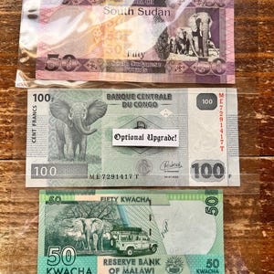 K&ouml;nnte beinhalten: Drei verschiedene Banknoten aus S&uuml;dsudan, Kongo und Malawi. Die s&uuml;dsudanische Banknote ist rosa und zeigt einen Elefanten. Die kongolesische Banknote ist gr&uuml;n und zeigt einen Elefanten. Die malawische Banknote ist gr&uuml;n und zeigt einen Elefanten und einen Gel&auml;ndewagen.