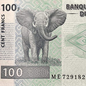 K&ouml;nnte beinhalten: Ein 100-Franc-Banknote aus Kongo mit einem Elefanten in der Mitte des Scheins. Der Text "BANQUE DU CONGO" ist in der oberen rechten Ecke gedruckt. Der Text "REPUBLIQUE DEMOCRATIQUE DU CONGO" wird in einem Kreis um den Rand des Scheins wiederholt. Der Text "ELEPHANT Parc National des VIRUNGA" ist unter dem Elefanten gedruckt. Der Text "100" ist in der unteren linken Ecke gedruckt und der Text "100" ist in der unteren rechten Ecke gedruckt. Der Text "ME 7291829" ist in der unteren rechten Ecke gedruckt.