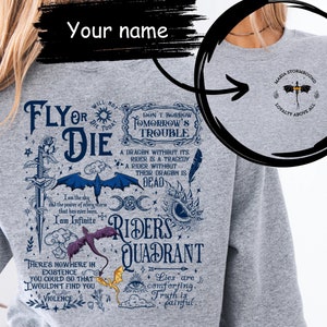 Könnte beinhalten: Grauer Pullover mit einem blauen und weißen Grafikdruck eines Drachen, eines Schwertes und einem Zitat, das "Fly or Die" lautet. Die Grafik enthält auch den Text "Don't Borrow Tomorrow's Trouble", "A Dragon Without Its Rider is a Tragedy", "A Rider Without Their Dragon is Dead", "Riders Quadrant", "Lies are comforting. Truth is painful.", und "Asia Stormbound Loyalty Above All".