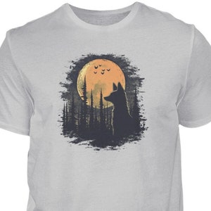 Op de afbeelding: Een grijs T-shirt met een afbeelding van een wolf silhouet dat huilt naar een volle maan met vleermuizen die eromheen vliegen. De maan is oranje en de achtergrond is een donker bos.