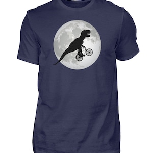 May include: A navy blue t-shirt with a graphic of a black silhouette of a dinosaur riding a bicycle in front of a full moon.