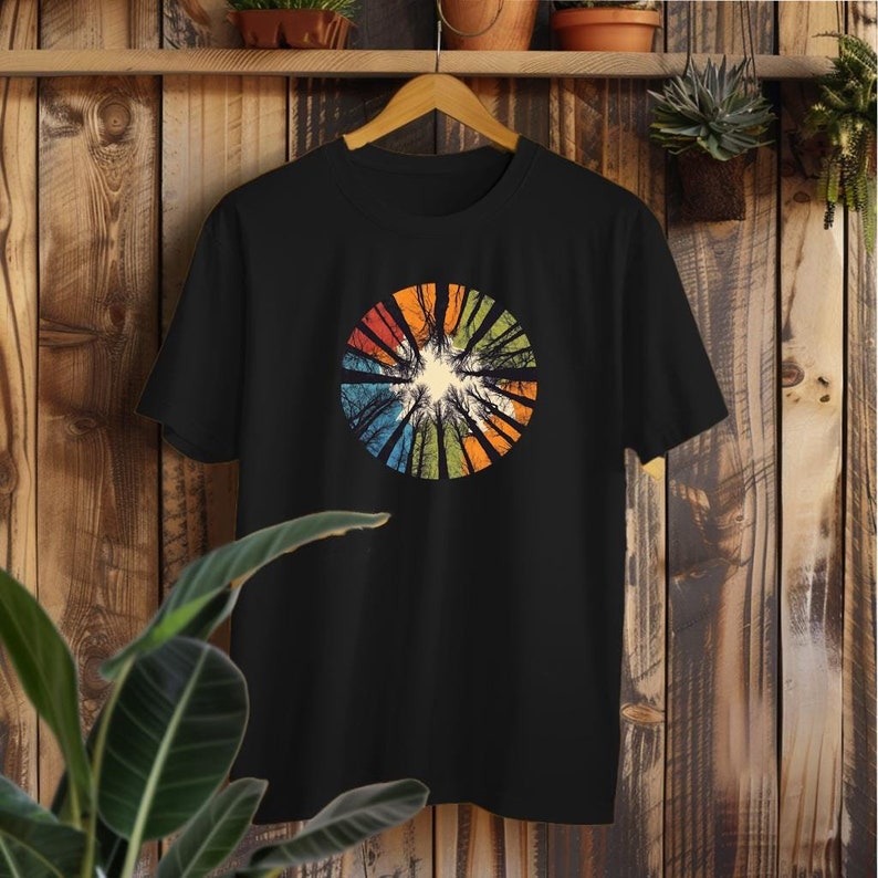 Może przedstawiać: Czarny T-shirt z kolorowym, okrągłym wzorem przedstawiającym sylwetkę drzew. Wz&oacute;r ma vintage'owy charakter i przypomina las.