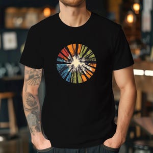 Może przedstawiać: Czarny t-shirt z kolorowym, okrągłym wzorem przedstawiającym widok drzew od dołu. Wz&oacute;r przypomina kalejdoskop.