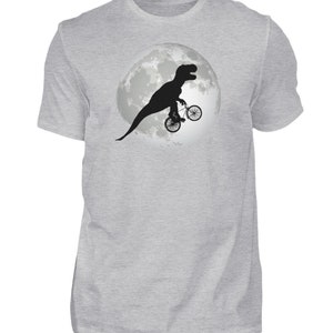 May include: A gray t-shirt with a black silhouette of a dinosaur riding a bicycle in front of a full moon.