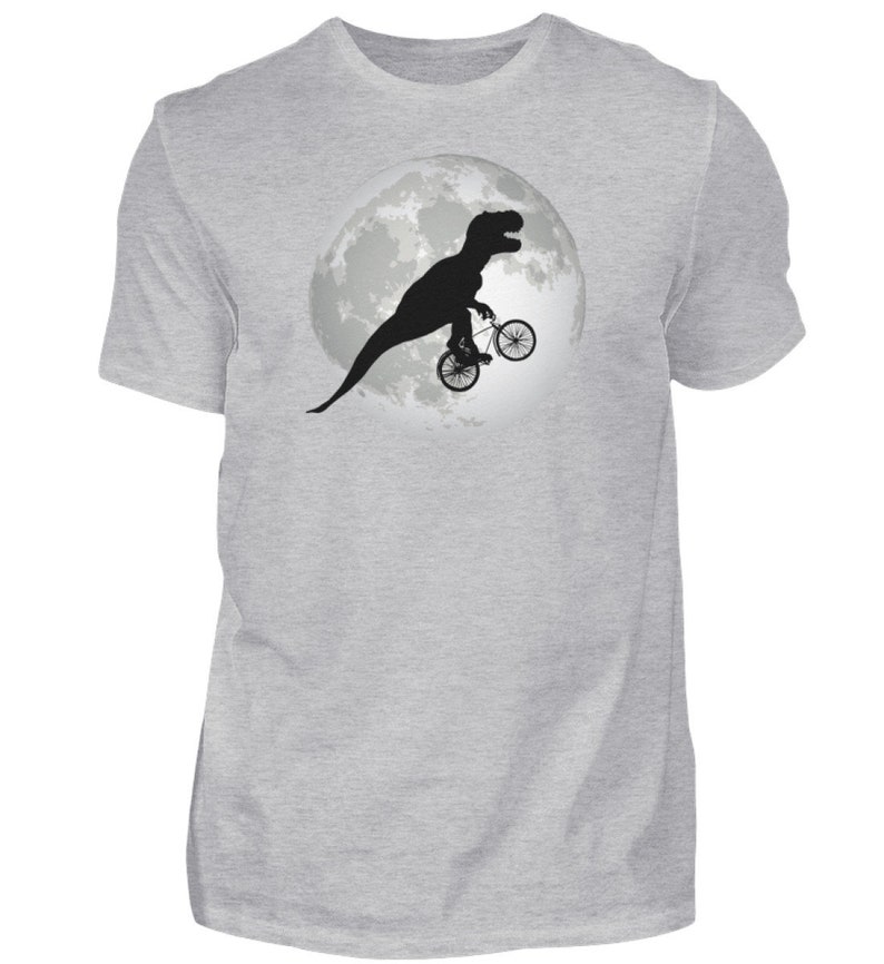 May include: A gray t-shirt with a black silhouette of a dinosaur riding a bicycle in front of a full moon.