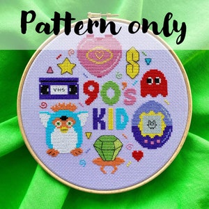 Puede incluir: Un patrón de punto de cruz con un fondo morado y una variedad de iconos de los 90, incluyendo un Tamagotchi, una cinta VHS, un anillo de caramelo, un fantasma de Pac-Man y las palabras "90's Kid".