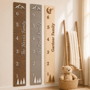 May include: Three vertical wooden growth charts featuring numerical markings from one to six feet. The dark brown board displays The Harris Family, the gray board shows The Smith Family, and the light wood board displays Gardner Family.