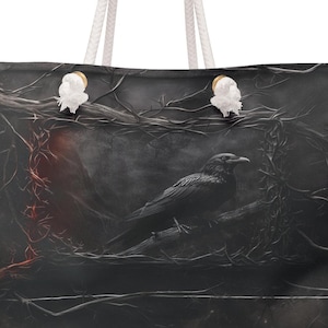 May include: A black tote bag with white rope handles and a dark, moody image of a raven perched on a branch with red and black accents.