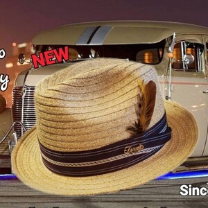 May include: A tan fedora hat with a black band and a brown feather. The hat has the word "Frank's" written on the band. The hat is in front of a vintage car and a woman wearing a black shirt. The text "Jefito Derby" and "NEW" are visible in the image. The text "Since 1932" is also visible in the image.