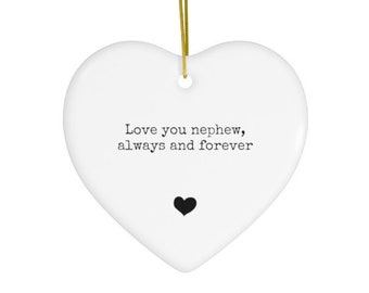 May include: White heart-shaped ornament with gold string. The ornament has the text "Love you nephew, always and forever" and a black heart. A decorative item for a nephew.