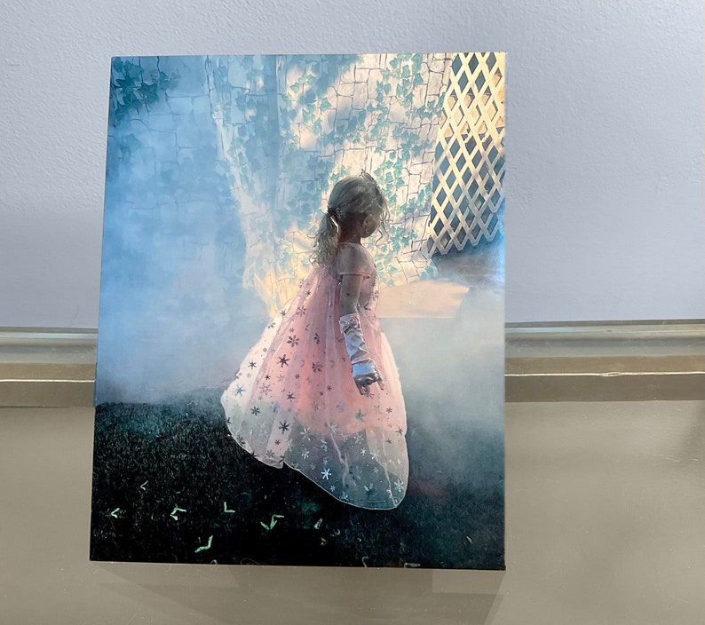 K&ouml;nnte beinhalten: Ein junges M&auml;dchen in einem rosa-wei&szlig;en Kleid mit silbernen Sternen, das vor einem gr&uuml;nen Hintergrund steht.