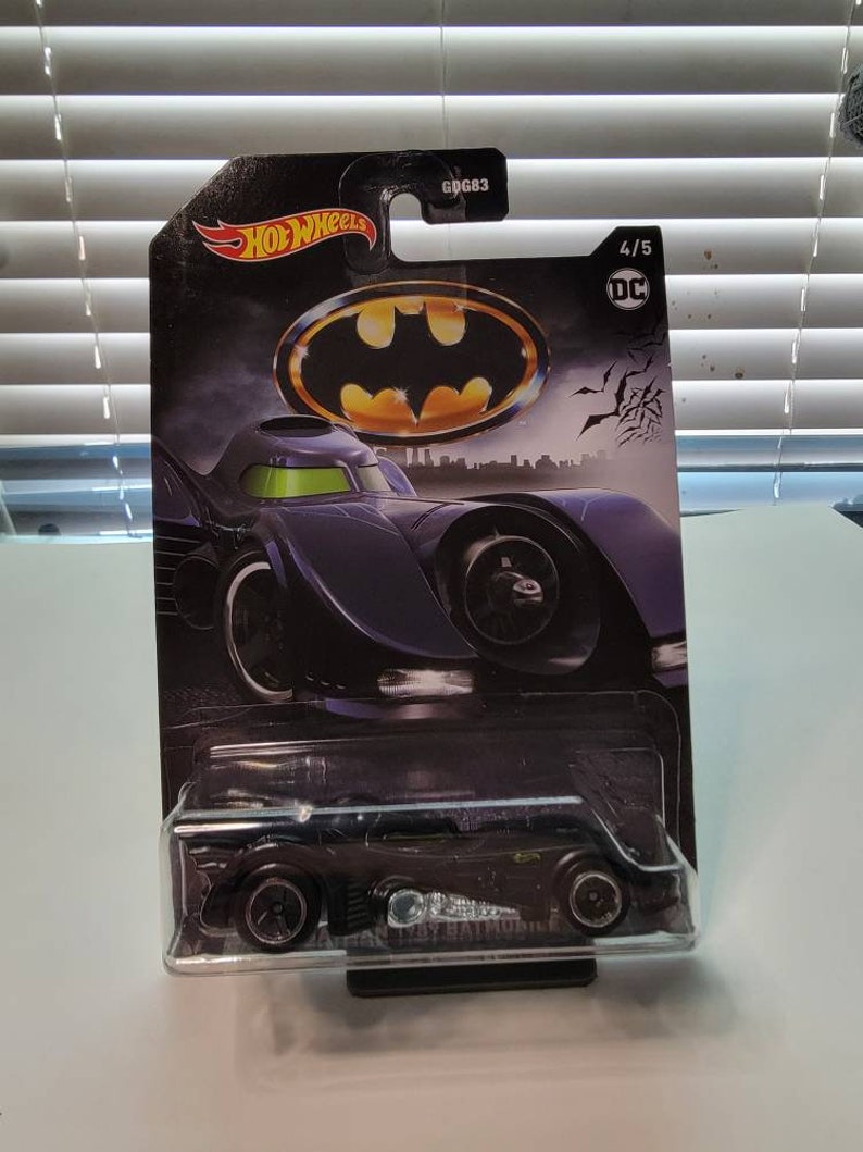 Pu&ograve; includere: Un'auto giocattolo nera in metallo pressofuso Hot Wheels della Batmobile di Batman del 1989. L'auto &egrave; in una confezione blister di plastica con un logo Batman nero e giallo. La confezione contiene anche il testo "Hot Wheels", "DC" e "4/5".