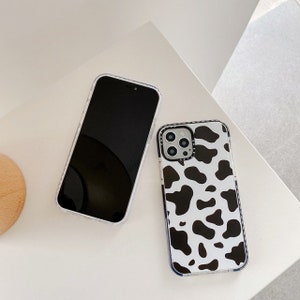 May include: Two clear phone cases, one with a black and white cow print design and the other with a black screen.