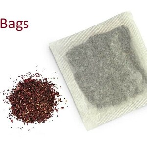 Op de afbeelding: Een close-up van een hoop losse gedroogde hibiscus thee en een enkel theezakje. De tekst "30 Tea Bags" is zichtbaar bovenaan de afbeelding.