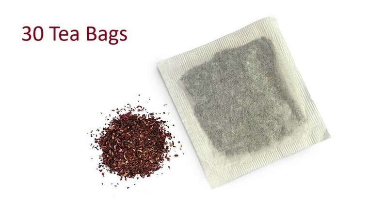 Op de afbeelding: Een close-up van een hoop losse gedroogde hibiscus thee en een enkel theezakje. De tekst "30 Tea Bags" is zichtbaar bovenaan de afbeelding.