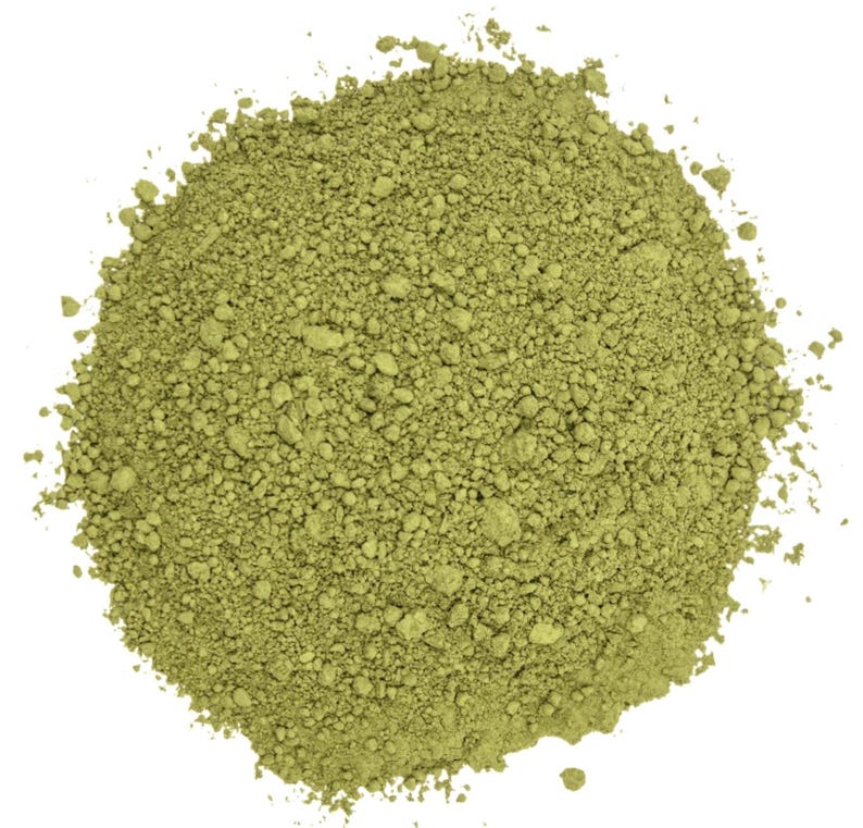 May include: A pile of finely ground, light green powder against a white background. The powder has a slightly granular texture, with small particles visible throughout. The overall color is a muted, earthy green.