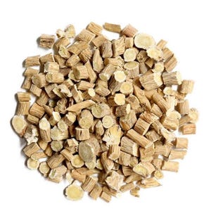 May include: A pile of chopped, dried Valerian root pieces. The pieces are cylindrical and beige, with a lighter, yellowish interior. The root pieces are scattered against a white background.