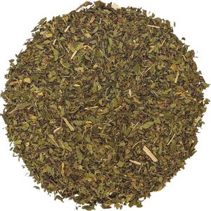 May include: A circular pile of dried, crushed green herbs featuring a mix of dark and light olive-green leaf fragments, small brown stems, and fine botanical particles arranged in a dense, textured mound against a plain white background.
