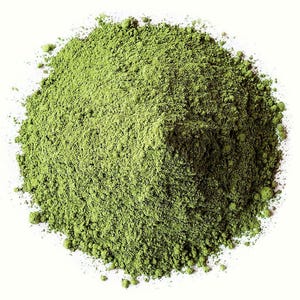May include: A pile of finely ground, vibrant green powder against a white background. The powder has a slightly textured appearance, suggesting a natural product. The color is a rich, verdant green, indicative of a plant-based ingredient.