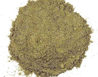 Pode incluir: Um monte de pó de ervas finamente moído, de cor verde-oliva, com uma textura grossa e fibrosa. A substância está empilhada em formato circular, exibindo variações de cor do verde claro ao escuro, com pequenas partículas visíveis por todo.
