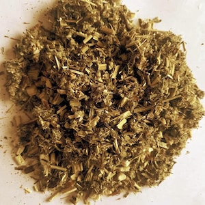 May include: A pile of dried, chopped herbs with a mix of light and dark brown tones. The texture appears coarse, with visible stems and leaf fragments. The image suggests a natural, organic product, possibly for culinary or medicinal use.